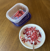 frozen raspberries crumbled onto a bowl of yogurt